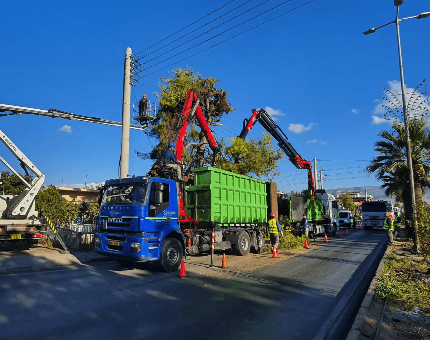 Συνεργείο με γερανοφόρο φορτηγό απομακρύνει κλαδιά από οδικό δίκτυο.